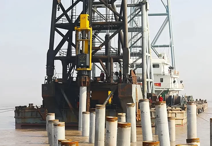 Pile hammers install deep foundations by delivering repeated impact energy that pushes piles into the ground. The amount of energy delivered affects penetration speed and final pile capacity. Photo Credit: JUWEl Machinery